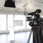 Professionelle Kamera auf Stativ für die Aufzeichnung und Live-Übertragung von Hybrid Events, ergänzt durch Studio-Lichttechnik.