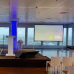 Rednerpult mit Mikrofon und Projektionsleinwand für eine Firmenveranstaltung, ausgestattet mit moderner Eventtechnik von EventTechnik nord.